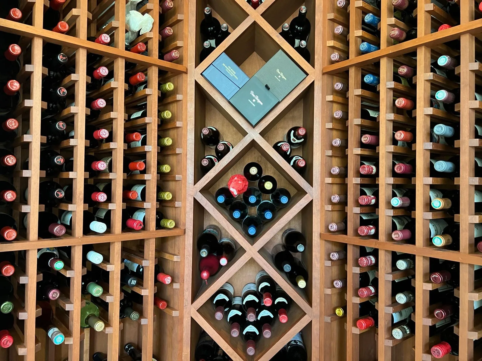 The wine room at 422 Addison Park Lane, wood racking floor to ceiling with single-bottle slots either side of a central column of X-braced diamond bins