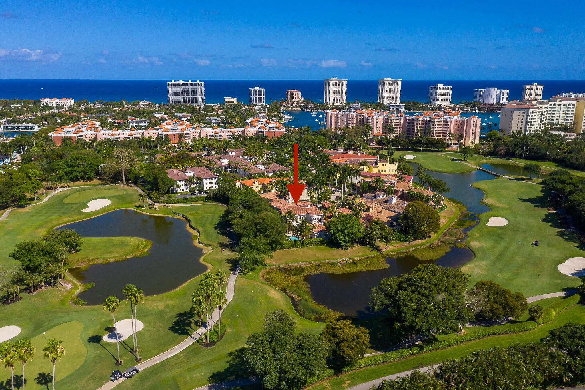 422 Addison Park Lane from the air, the house among the fairways, sand bunkers and ponds of the golf course with the Intracoastal and the coast beyond