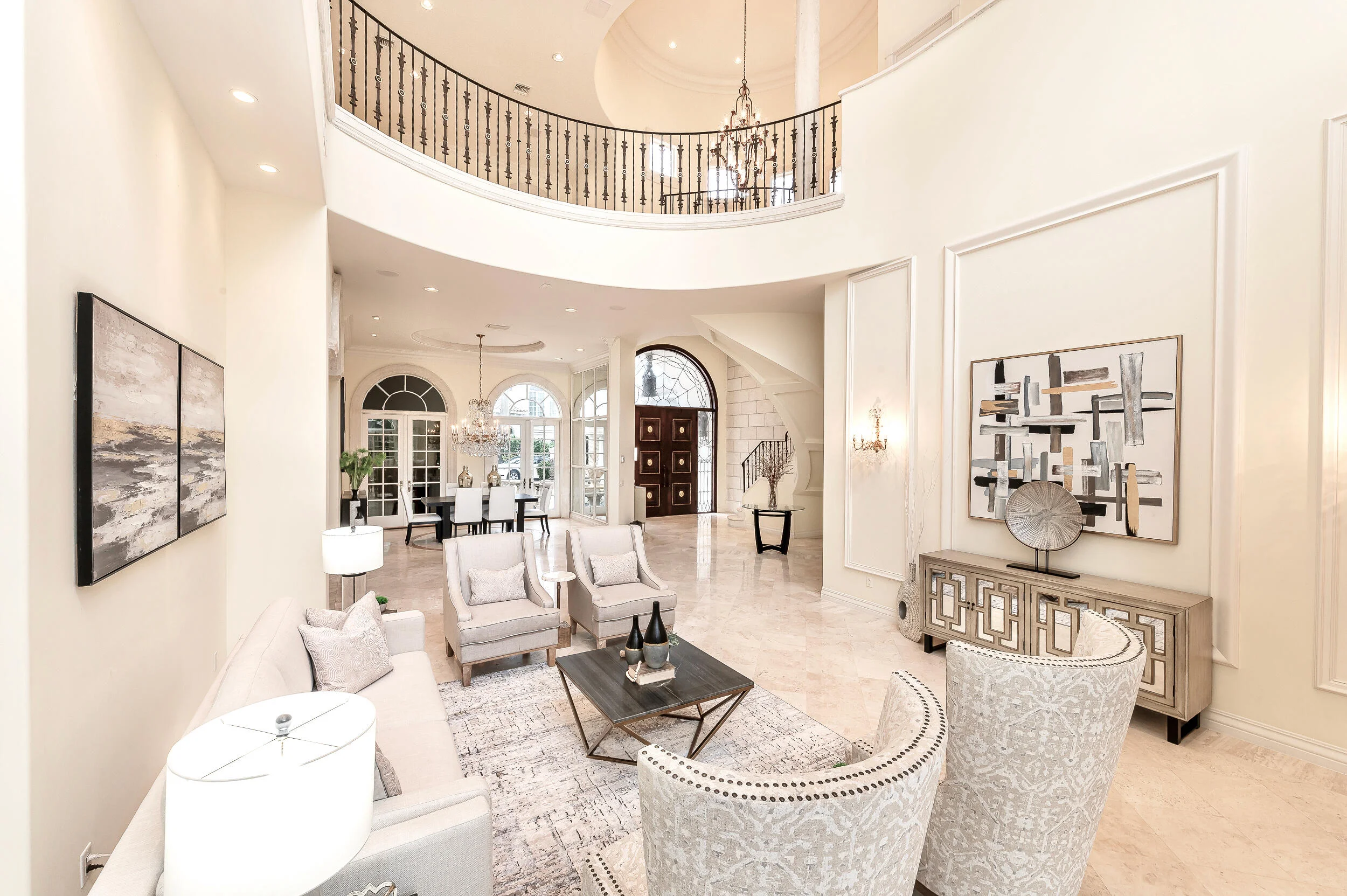 The two-storey living room at 422 Addison Park Lane, the gallery balustrade curving above and the entry beyond, with arched windows either side
