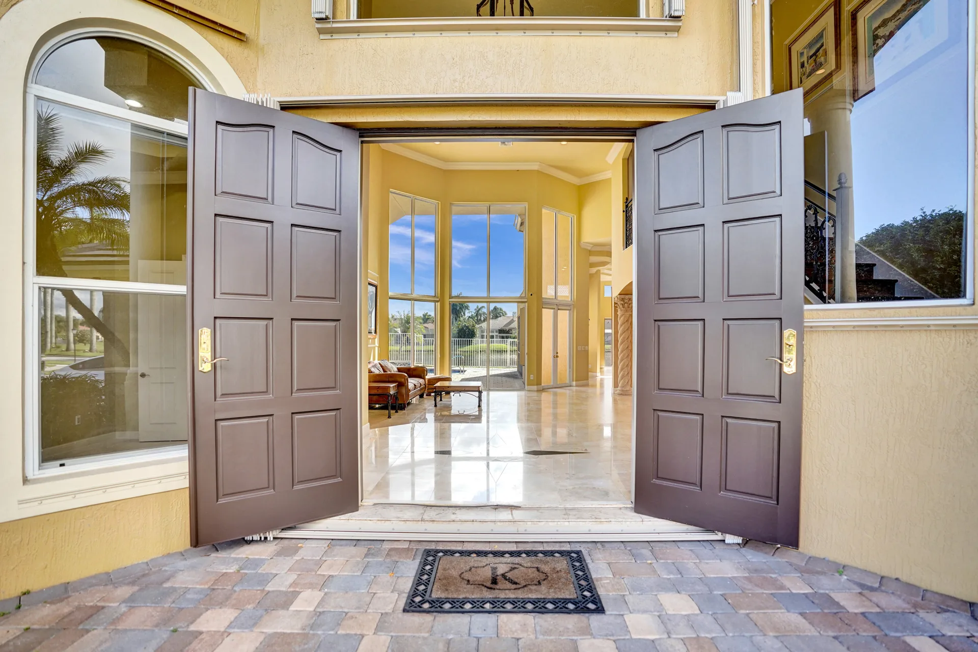 The open front doors of 6543 Newport Lake Circle, the view carrying through the house to the wall of glass, the pool terrace and the lake beyond