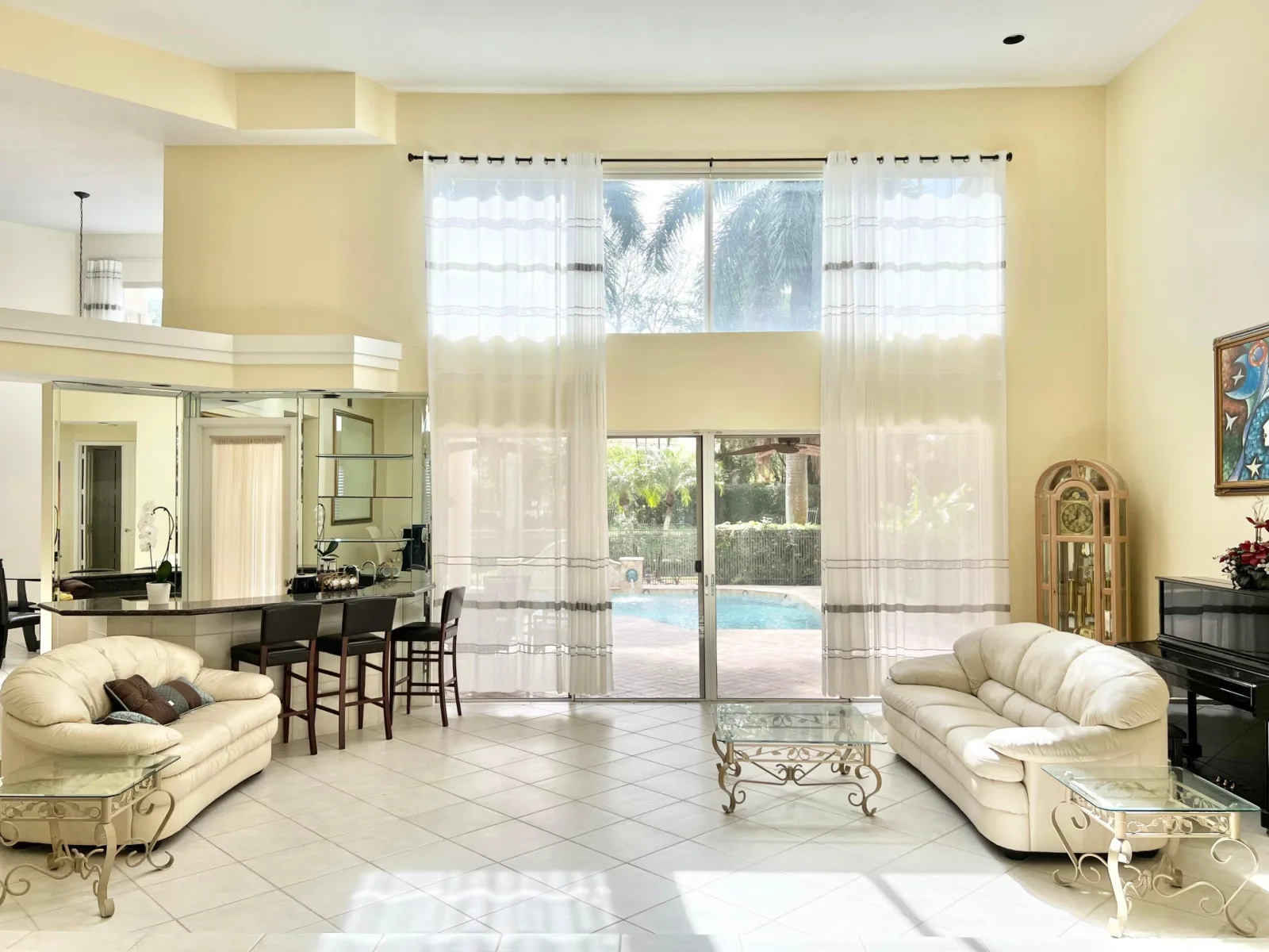 The sunken living room at 6662 Newport Lake Circle, full-height sliding glass topped by a second tier of glazing, with the raised bar and mirrored shelving to one side